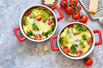Casserole with broccoli, tomatoes and parmesan on a concrete background. View from above.