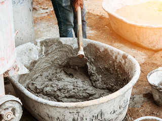 Mixing concrete by hands and spade in black basin in construction site