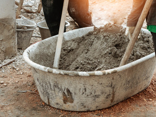Mixing concrete by hands and spade in basin
