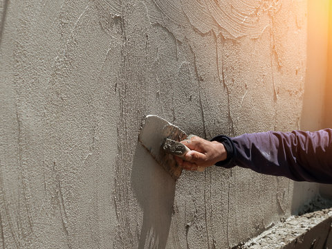 plasterer concrete worker at wall of house construction site