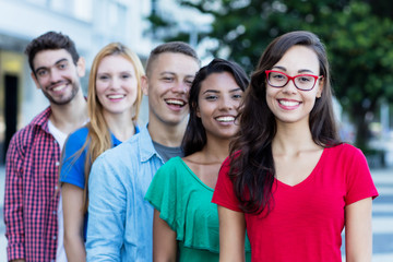 Junge Studentin mit Brille und Freunden in einer Reihe