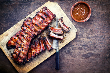 Barbecue spare ribs St Louis cut with hot honey chili marinade as top view on a rustic cutting...