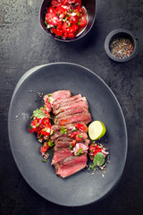 Traditional South American barbecue wagyu roast beef sliced with pico de gallo and salsa verde garnished as top view in a modern design plate