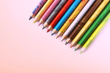 Color pencils on a pink background. Spectrum of a rainbow. Back to school. Selective focus, close-up.