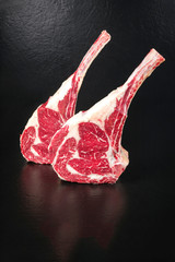 Raw dry aged wagyu tomahawk steak on black background with copy space