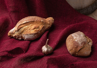 two loaves of bread and garlic on the background of colorful burlap,still life, closeup