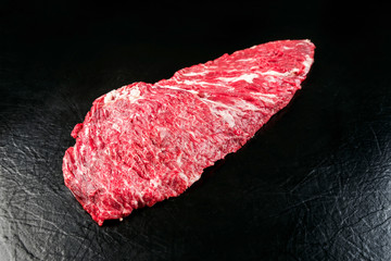 Raw wagyu skirt steak as closeup on black background with copy space