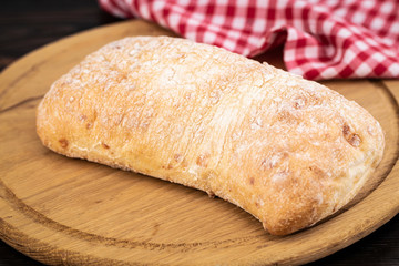 Loaf of ciabatta bread on a cutting board on the dark wooden table