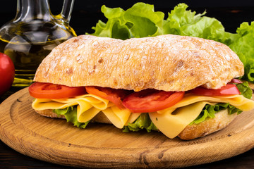 Ciabatta sandwich with lettuce , prosciutto and  cheese on wooden board