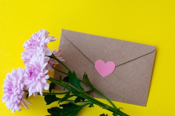 Love envelope with pink chrysanthemum flowers with pink heart on bright yellow bacground