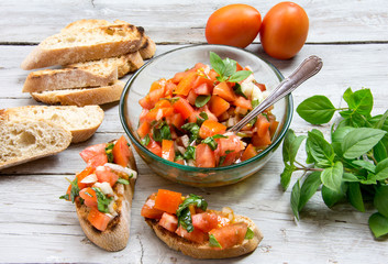 Ingredients to make bruschetta, typical Italian appetizer with tomato, basil and toast