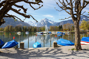 Boats covered with tarpaulin on Walensee lake on a sunny spring day. Weesen, Switzerland.