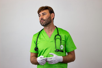 Portrait of male veterinary doctor in green uniform with brown hair looking sad, facing forwards...