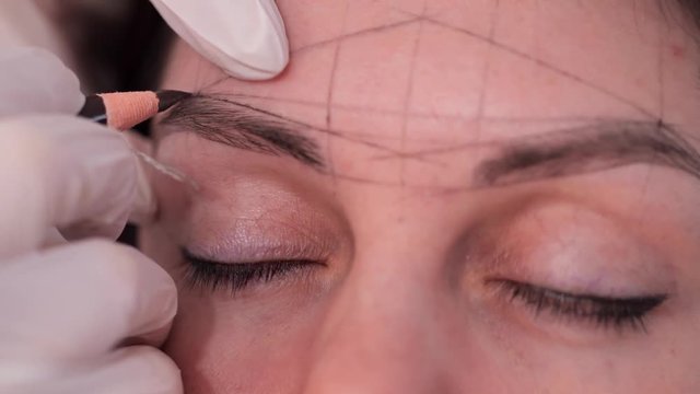 Specialist draw a sketch of eyebrows. Close-up of clear geometric shapes on the face. 4K Slow Mo