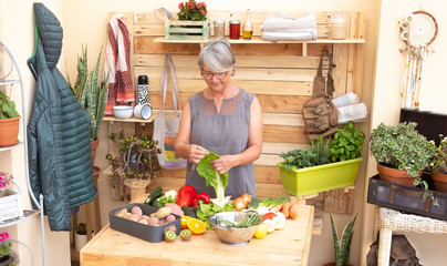 Senior people takes care of the vegetables harvested in the garden and prepares a vegetable soup. Elderly retired people, gray hair. Wooden table and background
