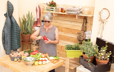 Old people woman gray hair cleans and takes care of the vegetables of her garden preparing a vegetable soup. Elderly people. Wooden table and background. Vintage style