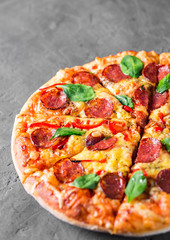 Pepperoni Pizza with Mozzarella cheese, salami, pepper, Spices and Fresh spinach. Italian pizza on Dark grey black slate background