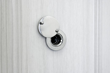 Door peephole from the chromeplated steel in an entrance door from white wood of an oak