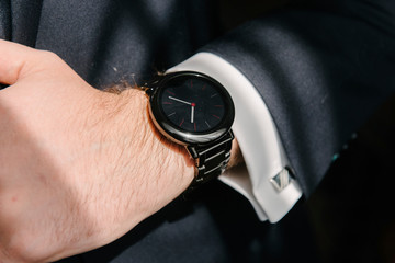 Man in suit with hand adjusts sleeve of shirt close-up