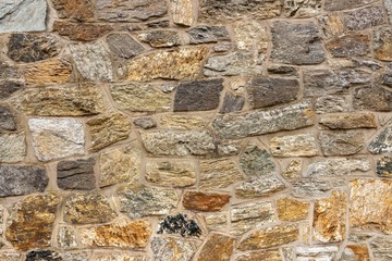 The texture of the stone wall, elements of brown, orange, gray and black. Original background, abstract pattern