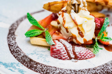 Close up delicious dessert with waffle rolls, ice cream and strawberries