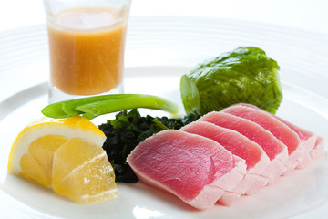 Sashimi plate isolated on white background. Tuna sliced ​​slices on a white plate with lemon on a white background.