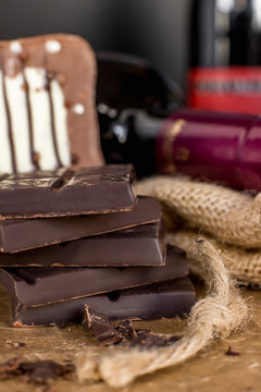 Close-up of stacked dark and milk chocolate on burlap, with wine 