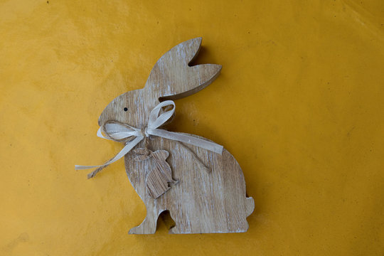 blick auf einen osterhasen aus holz auf gelbem hintergrund fotografiert an Ostern an einem sonnigen Tag im Emsland