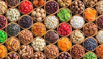 assorted nuts and dried fruit background. organic food in wooden bowls, top view. - obrazy, fototapety, plakaty