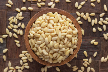 cedar nuts peeled in wooden bowl, top view.