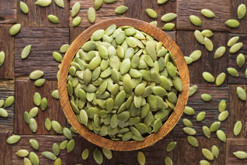 pumpkin seeds peeled in wooden bowl, top view.