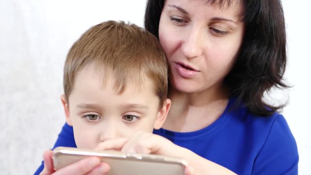Happy family: Mom and son hold a smartphone and play with the application for children on the Internet