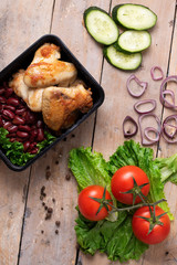 fried chicken wings, grilled meat and beans with red onion rings, salad leaves and cucumber slices