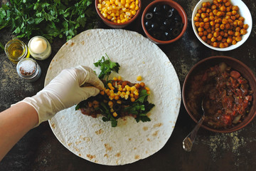 Cooking vegan shawarma. Hands in culinary gloves impose a filling in pita bread for making shawarma. Middle Eastern cuisine.