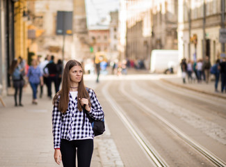 Young tourist woman with backpack walk by street in old europe city, summer fashion style