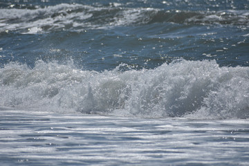 A foamy ocean wave creating sprays of water as it crashes into the shore.