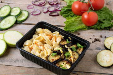 ready meal to eat in lunch boxes, raw vegetables around, food containers on wooden table