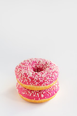 Two donuts with pink icing on a white background