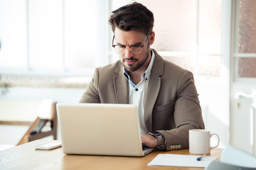 Handsome young business man working with laptop in the office.