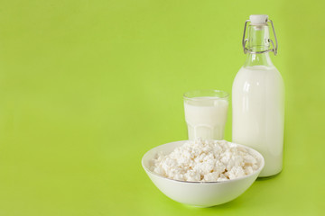 milk in a bottle cottage cheese and a glass of milk on a green background