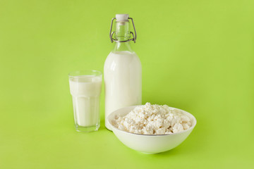 milk in a bottle cottage cheese and a glass of milk in the center of the frame on a green background