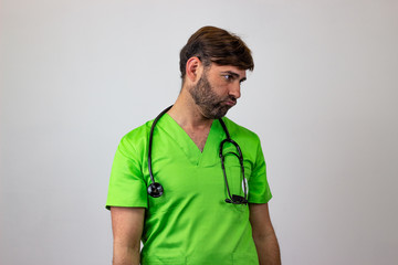 Portrait of male veterinary doctor in green uniform with brown hair frustated, facing forwards and...