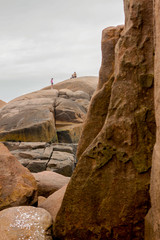 Homem sentado no topo de uma rocha gigante observando a paisagem 
