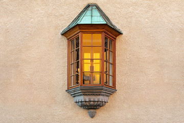 Obraz premium The window in the form of a bay window is located in the middle of the plastered wall of the building