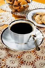 A cup of coffee, lace doily, wooden table, rustic style. Selective focus