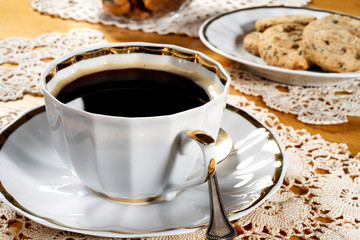 A cup of coffee, lace doily, wooden table, rustic style. Selective focus