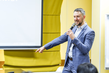 Assertive male politician speaking into microphones on political convention. Speaker on the podium