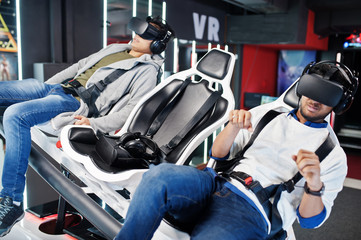 Two young indian people having fun with a new technology of a vr headset at virtual reality simulator.