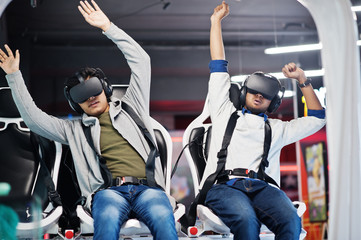 Two young indian people having fun with a new technology of a vr headset at virtual reality simulator.