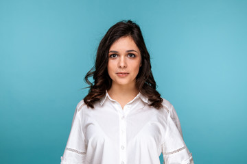 Portrait of pretty smiling girl in a white blouse isolated over the blue background